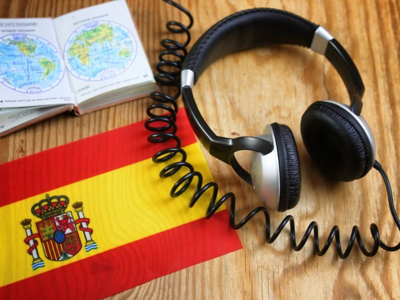 nauka języka hiszpańskiego - biurko, na którym leży flaga słuchawki i zeszyt